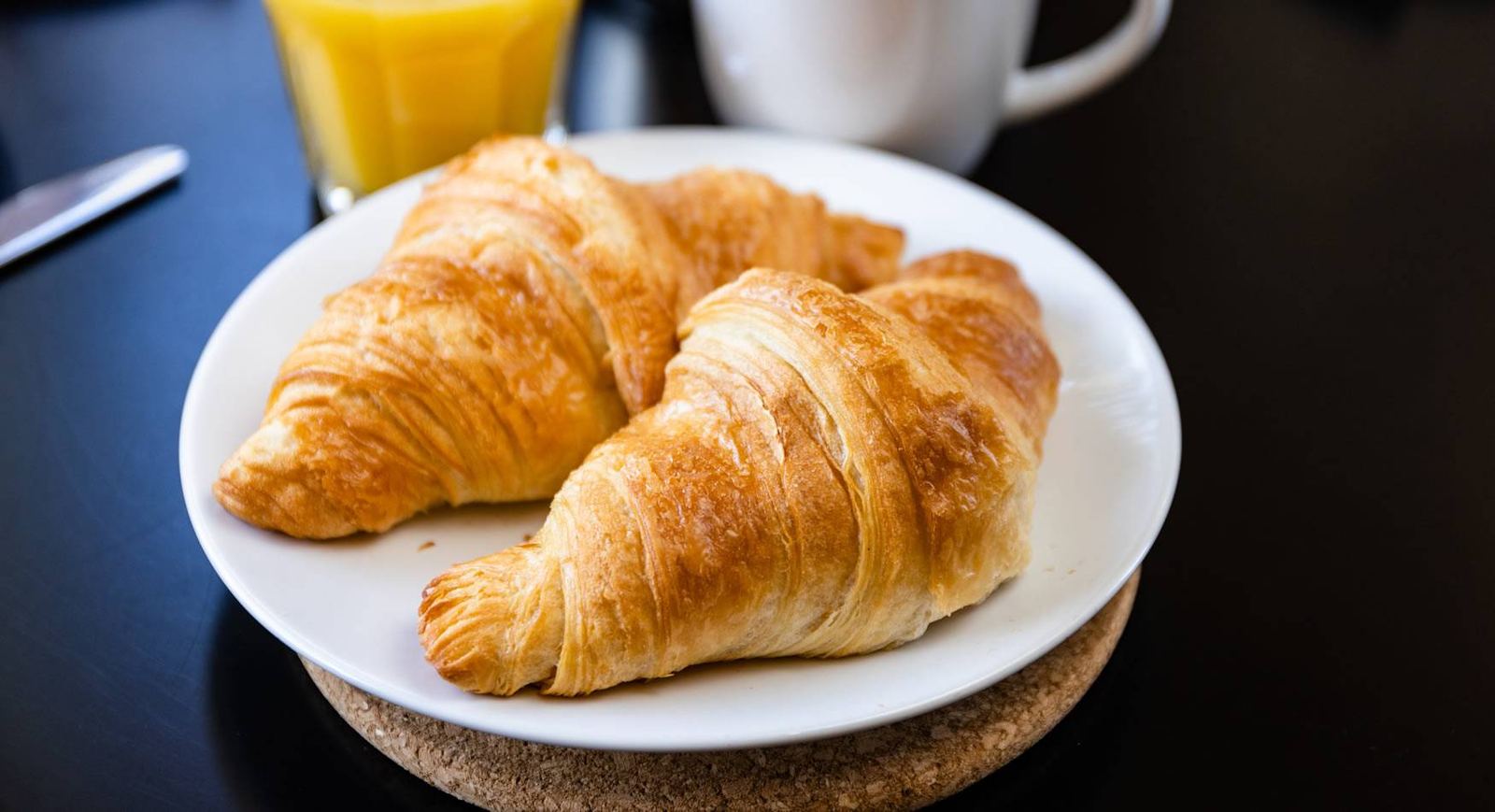 Two golden croissants with orange juice and coffee