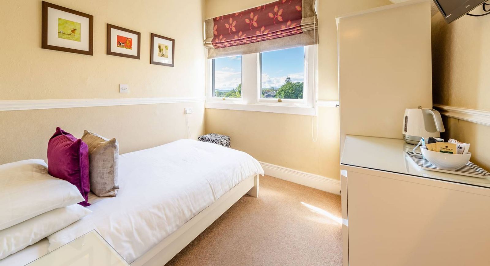 Single bedroom with single bed, autumn-leaf Roman blind, framed prints and tea and coffee tray